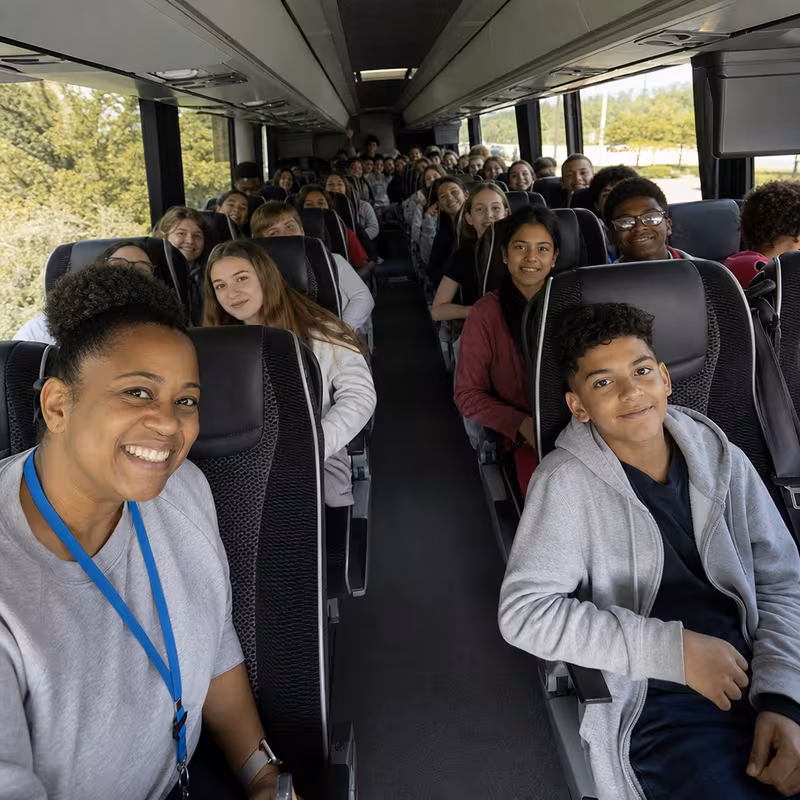 Group boarding a white charter bus for School Transportation transportation in Toledo