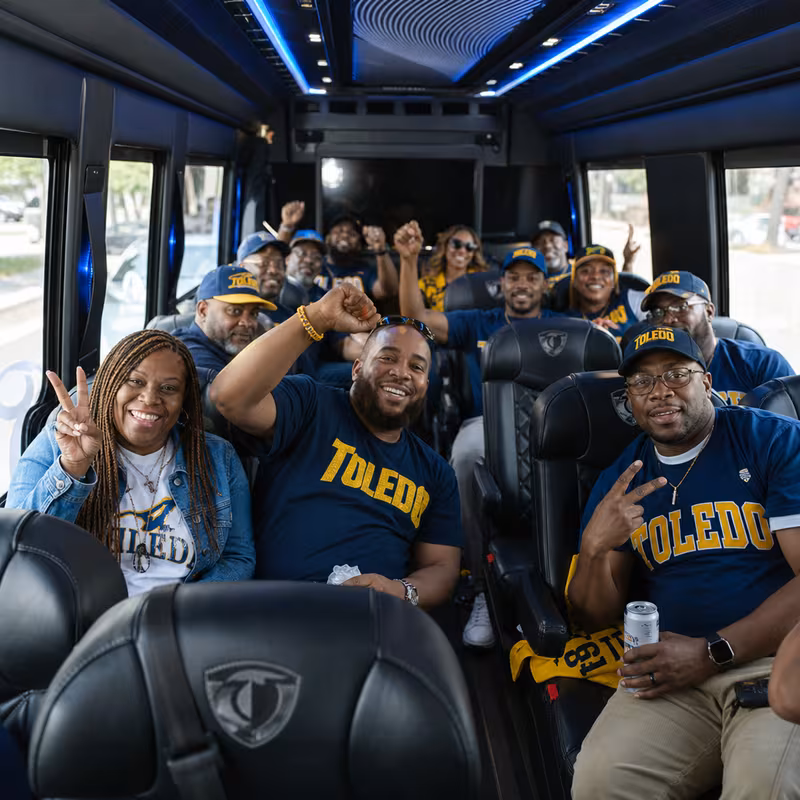 Group boarding a white charter bus for Sporting Event Transportation transportation in Toledo